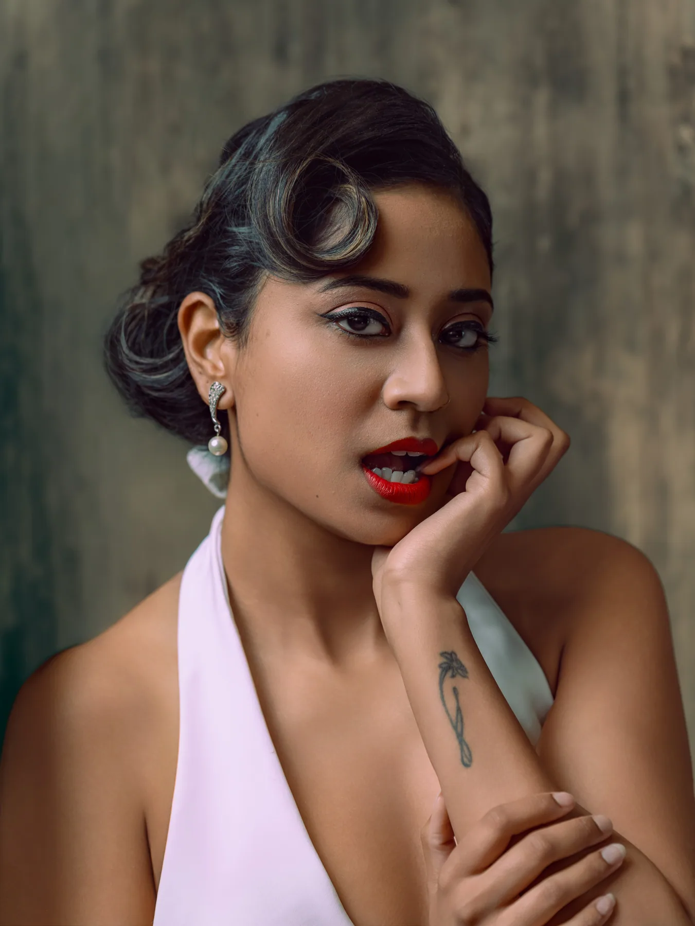 Editorial beauty portrait with graphic black eyeliner, red lips, vintage waves, and pearl earrings