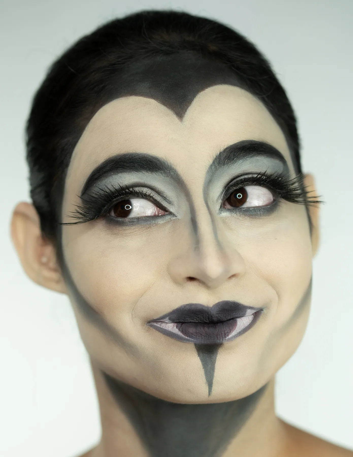 Graphic SFX character makeup with monochrome face shaping, dramatic lashes, and a stylized theatrical expression